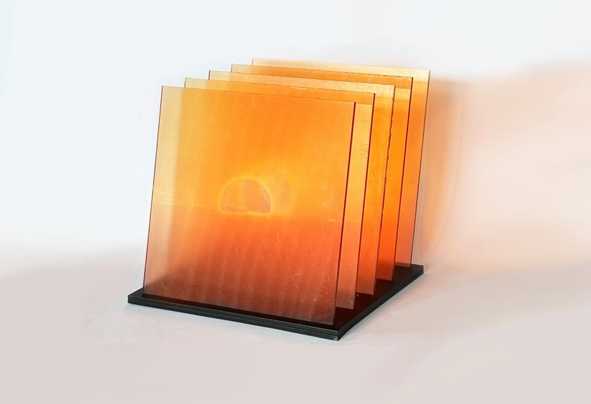 An illuminated orange layered installation standing on a black base